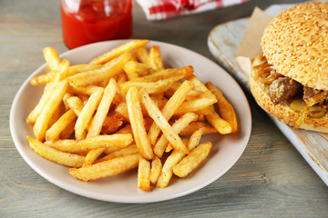 Tasty sandwiches and french fries on plate, on wooden background. Unhealthy food concept