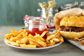 Tasty sandwiches and french fries on plate, on wooden background. Unhealthy food concept