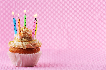 Birthday cupcake with candles on color background