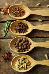 Wooden spoons with fresh herbs and spices on wooden background