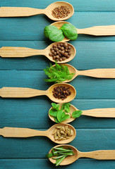 Wooden spoons with fresh herbs and spices on wooden background