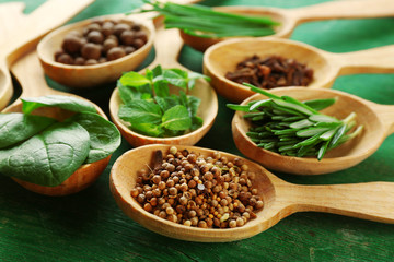 Wooden spoons with fresh herbs and spices on wooden background