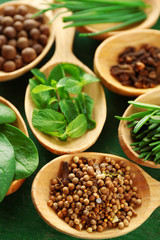 Wooden spoons with fresh herbs and spices on wooden background