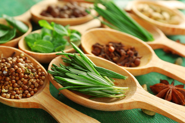 Wooden spoons with fresh herbs and spices on wooden background