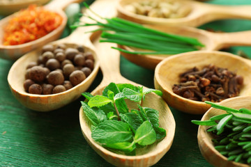 Wooden spoons with fresh herbs and spices on wooden background