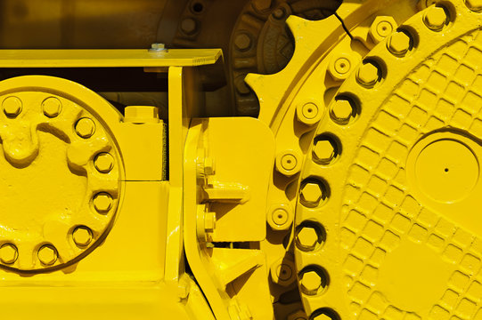 Caterpillar drive gear, bulldozer sprocket mechanism, large construction machine with bolts and yellow paint coating, heavy industry, detail 