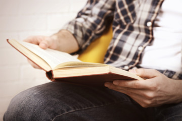 Young man reading book, close-up, on light background