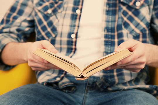 Young man reading book, close-up, on light background