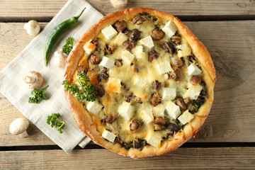 Cheese pie with mushrooms, herbs and sour creme, on wooden table background
