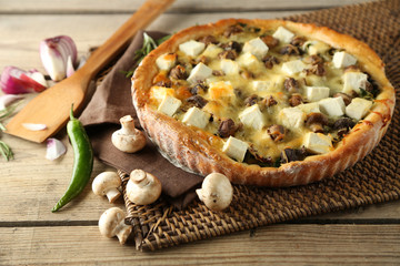 Cheese pie with mushrooms, herbs and sour creme, on wicker mat, on wooden table background