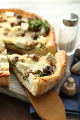 Cheese pie with mushrooms, herbs and sour creme, on napkin, on wooden table background