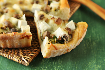Cheese pie with mushrooms, herbs and sour creme, on wicker mat, on wooden table background
