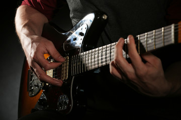 Fototapeta premium Young man playing on electric guitar close up