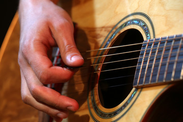 Fototapeta premium Young man playing on acoustic guitar close up