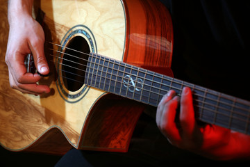 Fototapeta premium Young man playing on acoustic guitar close up