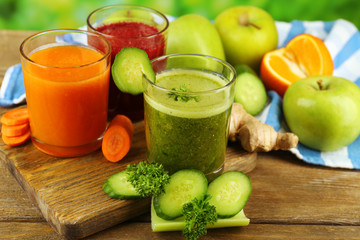 Assortment of healthy fresh juices on wooden table, on bright background