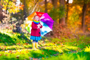 Little girl playing in the rain in autumn