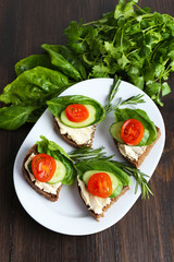 Delicious sandwiches with vegetables and greens on wooden table