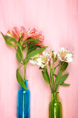 Beautiful alstroemeria in vases on wooden background
