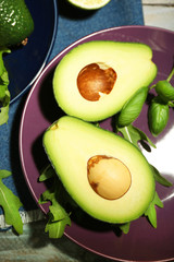 Sliced avocado, arugula and lemon lime on wooden background