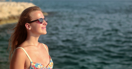 Girl standing on the cliff and splashed with water, enjoying the sun