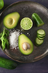 Sliced avocado, cucumber/ pepper and lemon lime on wooden background