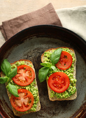 Vegan sandwich with avocado and vegetables on pan, on wooden background