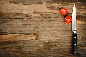 Halves of tomato with knife on wooden background