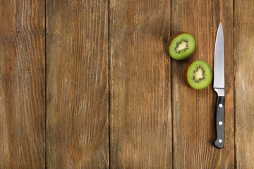 Halves of kiwi with knife on wooden background