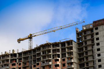 High brick building construction crane against the blue sky