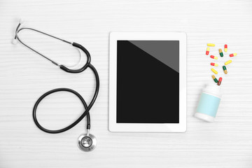 Medical tablet with stethoscope on wooden background