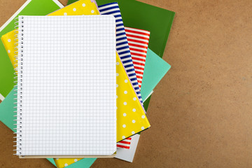 Notebook on top of pile of books and magazines on wooden background