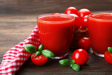 Glasses of tomato juice with vegetables on wooden background