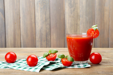 Glass of tomato juice with vegetables on wooden background