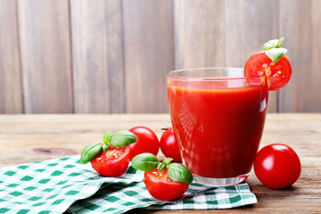 Glass of tomato juice with vegetables on wooden background