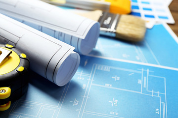 Construction instruments, plan and brushes on wooden table background