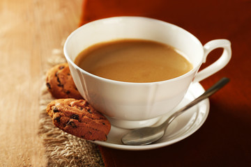 Cup of coffee with cookie on table, closeup