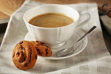 Cup of coffee with cookie on table, closeup