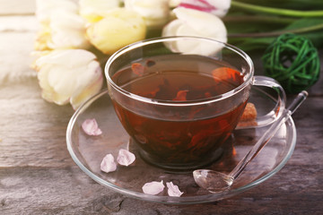 Cup of herbal tea with tulips on wooden table, closeup