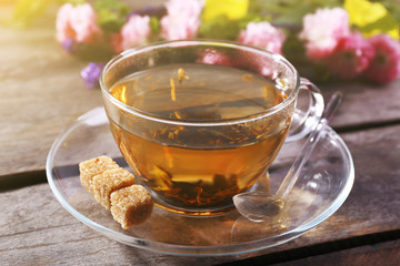 Cup of herbal tea with flowers on wooden table, closeup