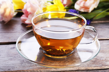 Cup of herbal tea with flowers on wooden table, closeup