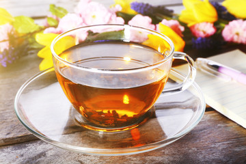 Cup of herbal tea with flowers on wooden table, closeup