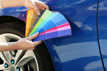 Female hands with paint samples choosing color for painting car, closeup
