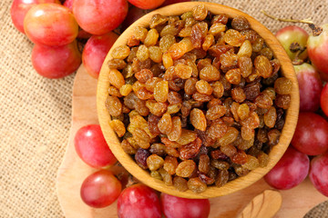 Raisins in bowl with grapes on table close up