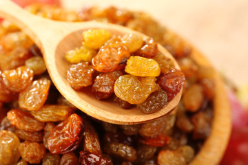 Raisins in bowl with grapes on table close up