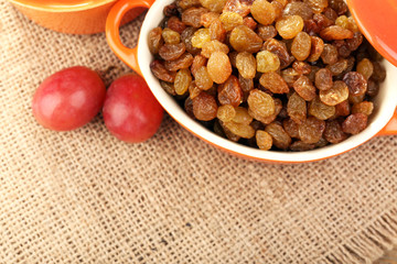Raisins in bowl with grapes on table close up
