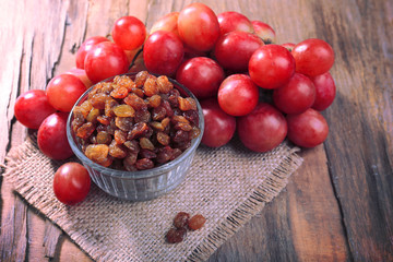 Raisins in bowl with grapes on table close up