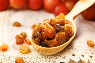 Raisins in wooden spoon with grapes on table close up