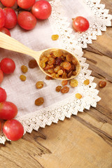 Raisins in wooden spoon with grapes on table close up