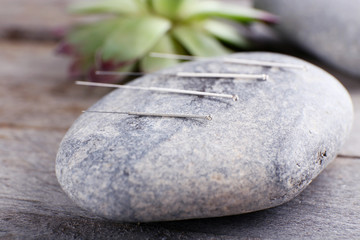 Needle for acupuncture on spa stones on table close up